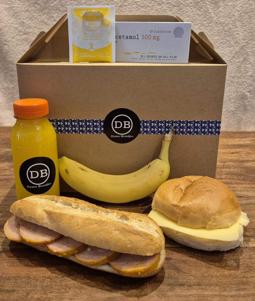 Kater onbijtbox met een flesje jus d'orange, paracetamol, yogi tea detox, een banaan, een belegde minibaguette en een belegd zacht bolletje